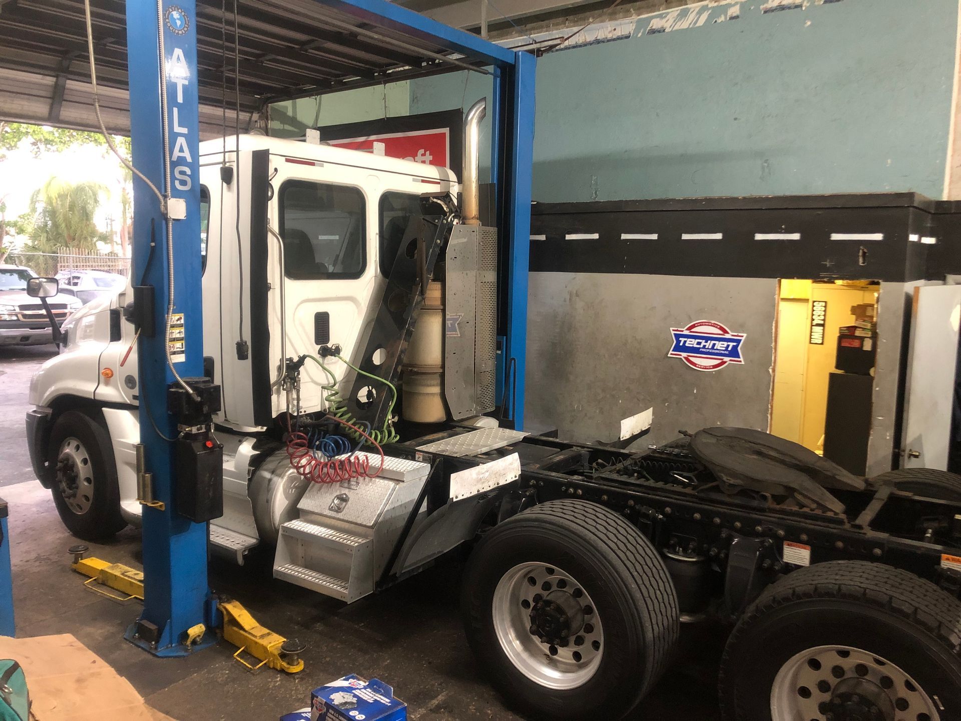 A semi truck is sitting on a lift in a garage.