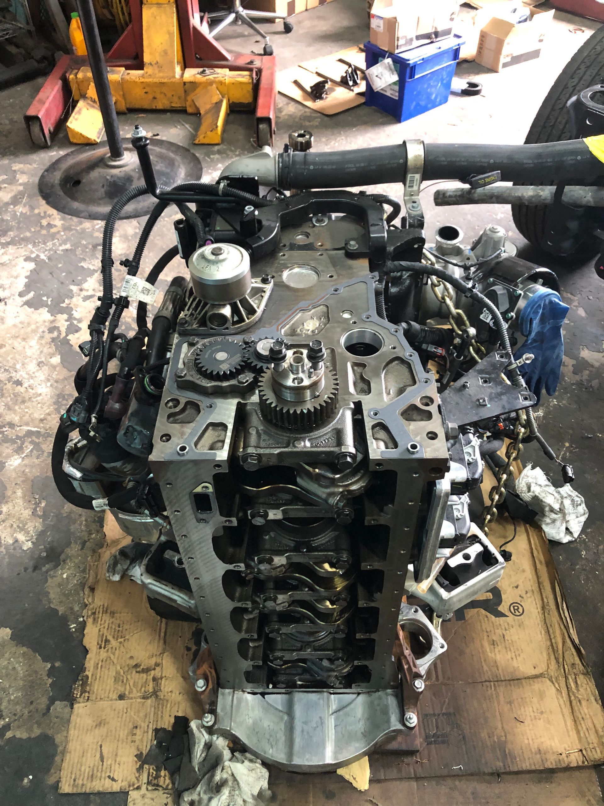 A large engine is sitting on top of a cardboard box in a garage.