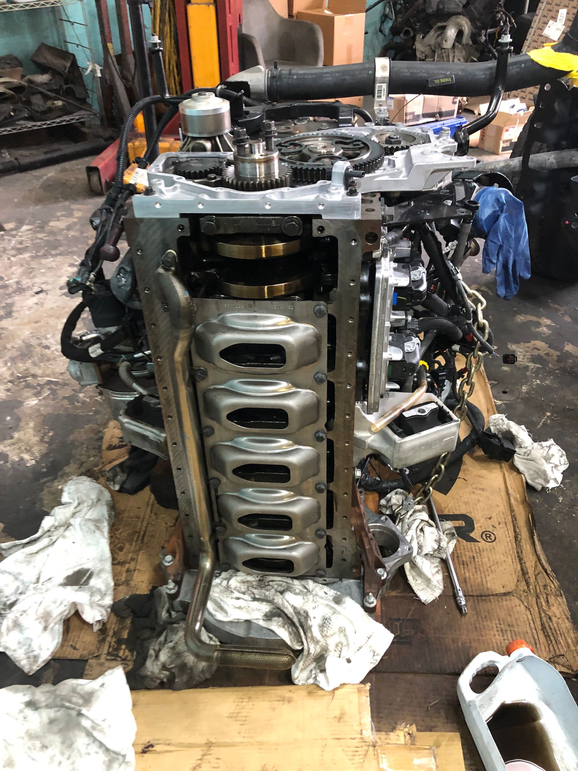 A car engine is sitting on top of a cardboard box in a garage.