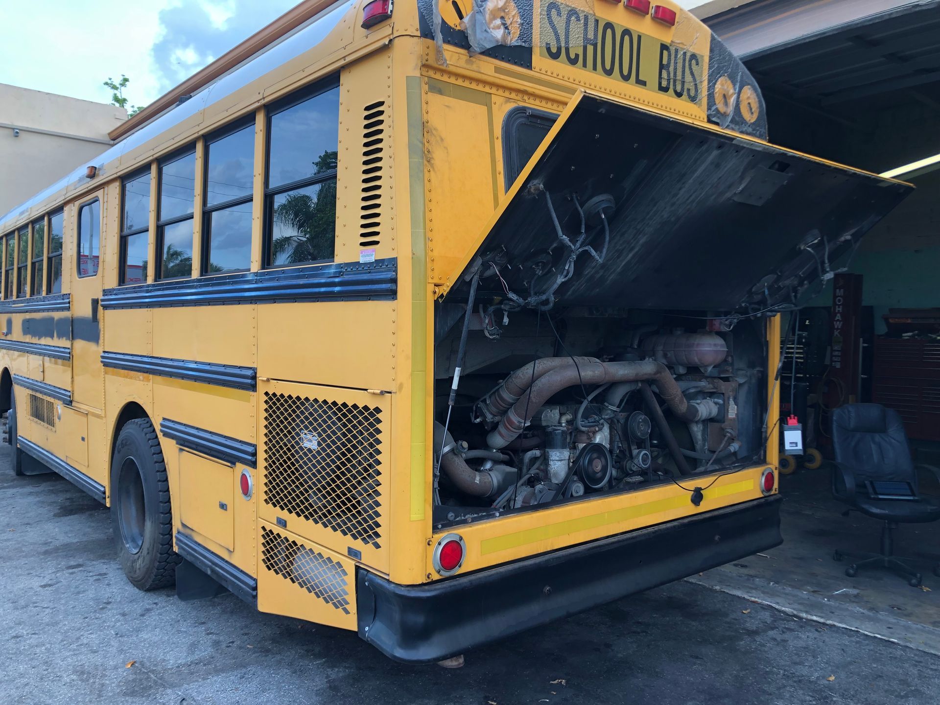 A yellow school bus with its hood open