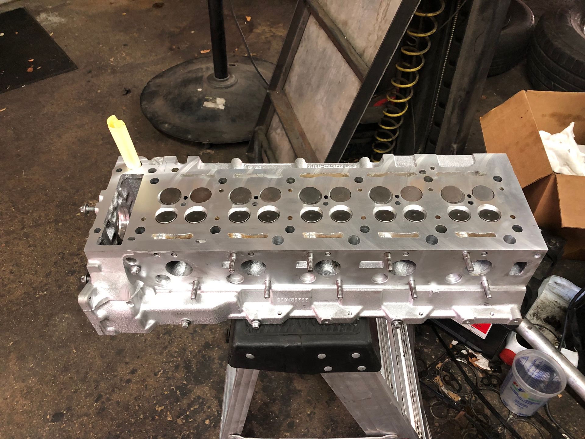 A cylinder head is sitting on a ladder in a garage.