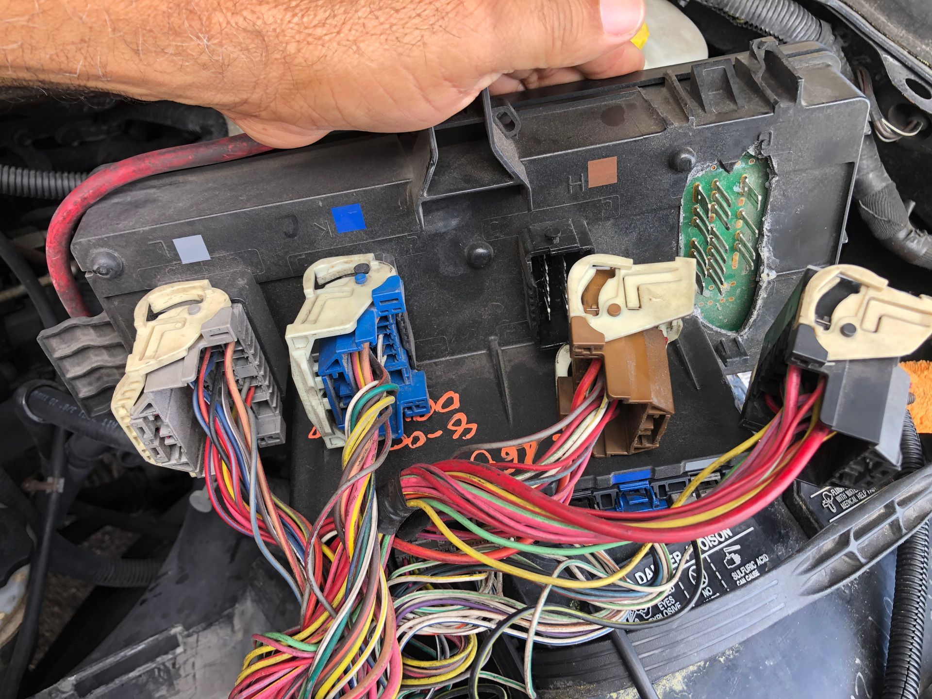 A person is working on a fuse box in a car.