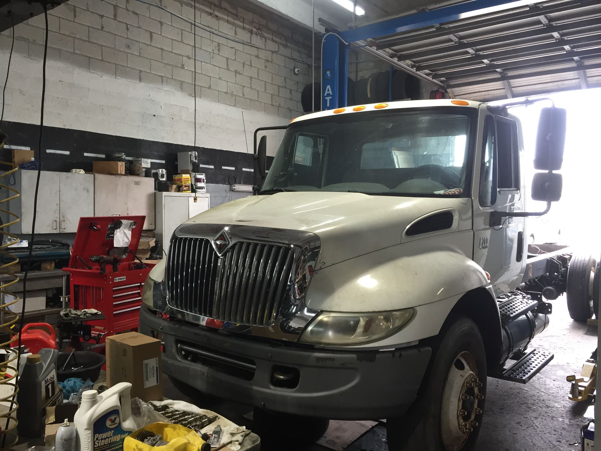 A white truck is sitting on a lift in a garage.