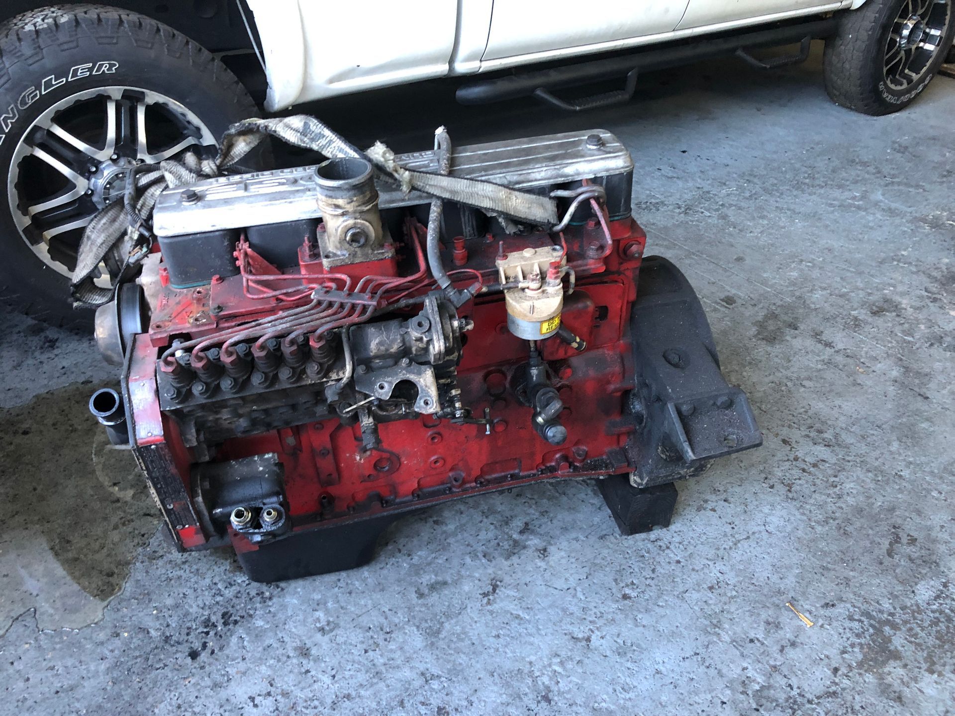 A red engine is sitting on the ground next to a white truck.