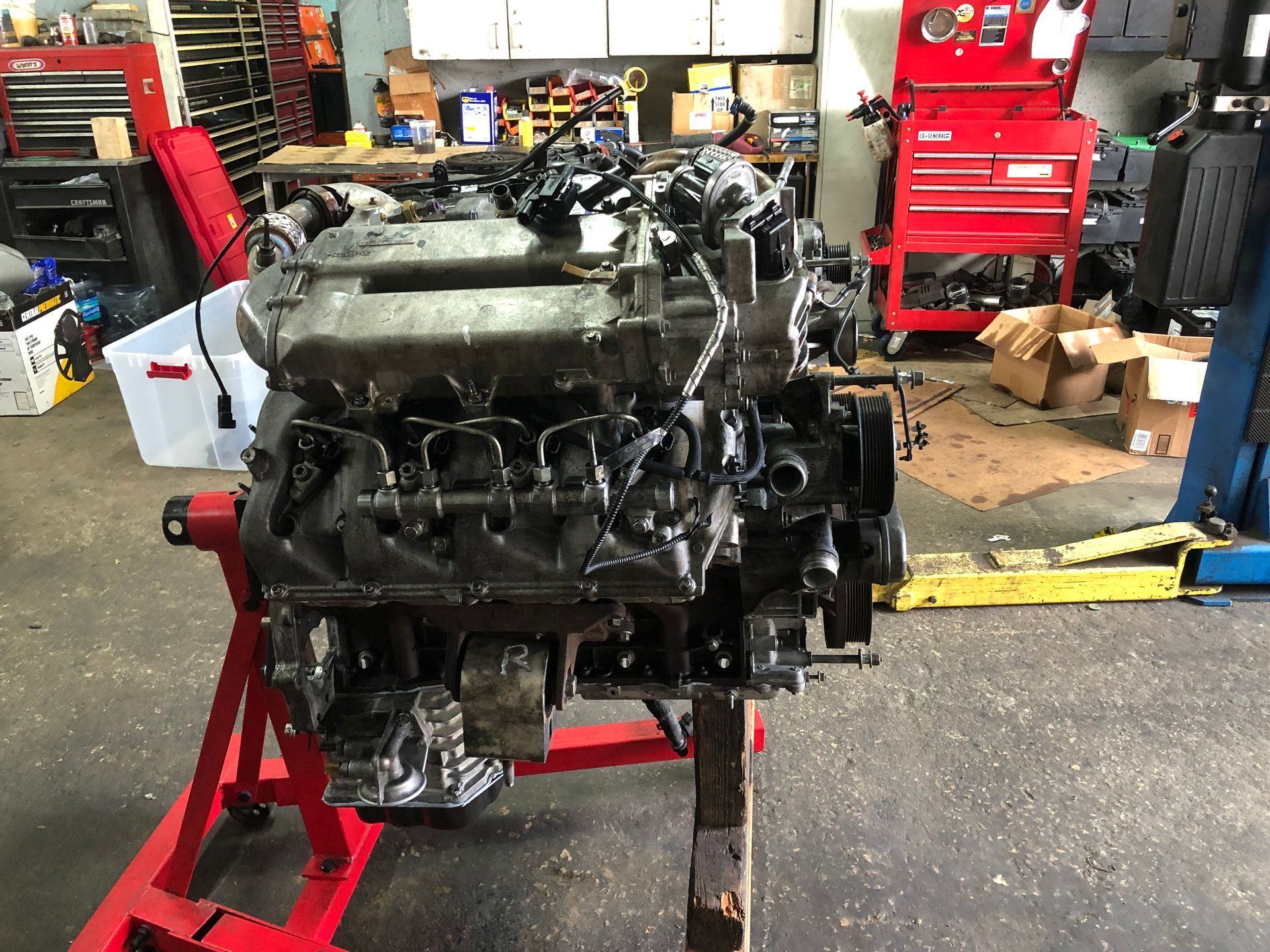 A car engine is sitting on a red stand in a garage.