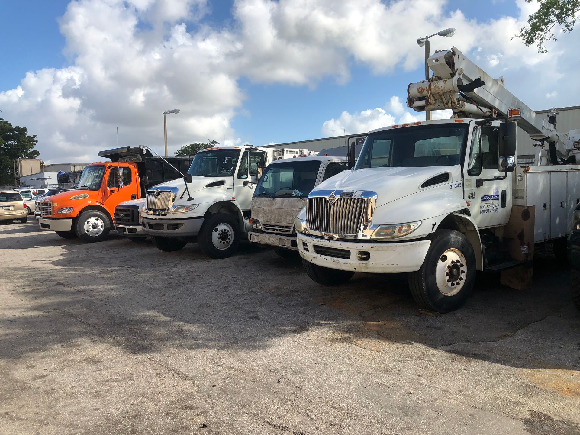 A row of trucks are parked in a parking lot.