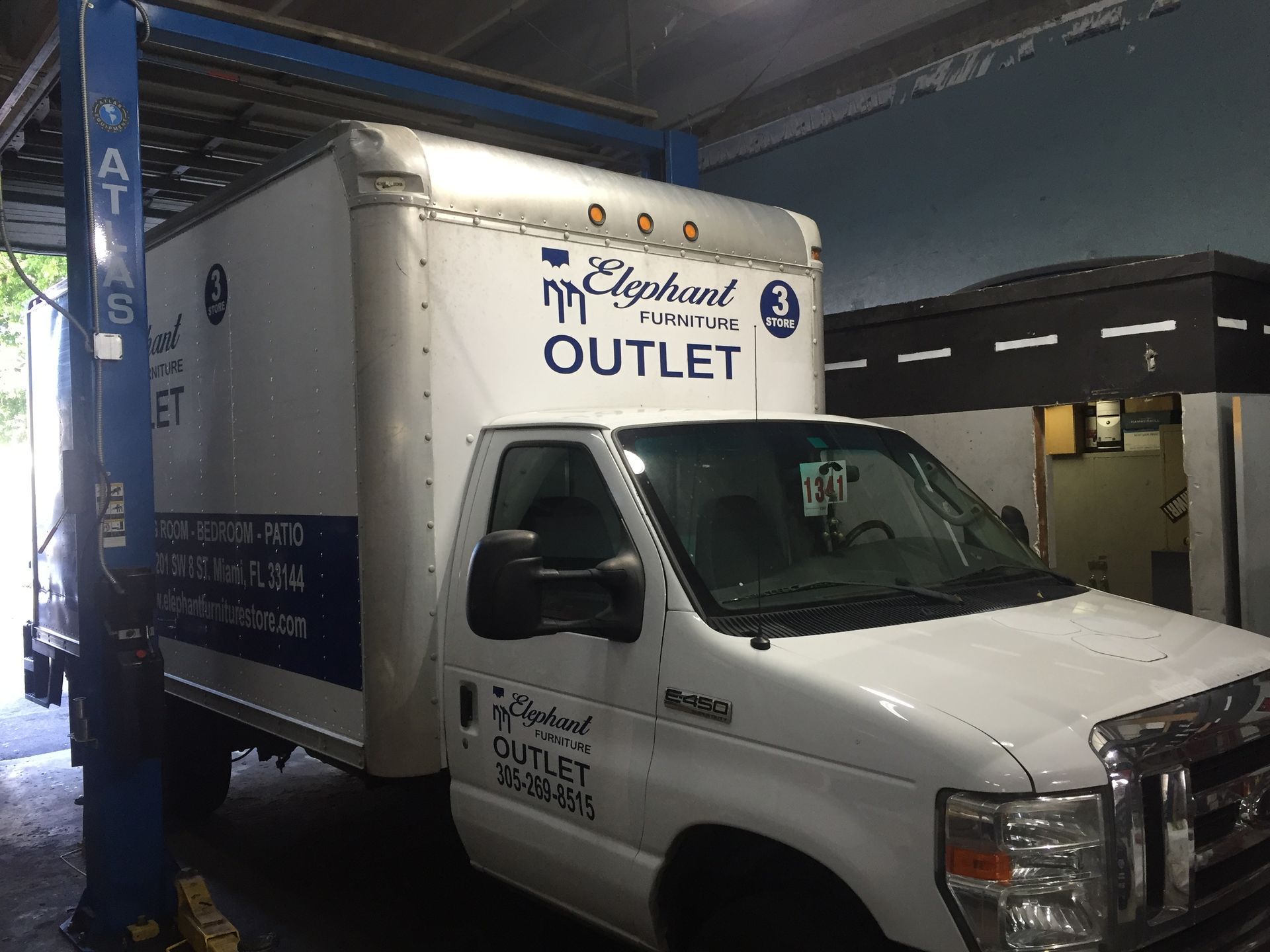 A white truck with the word outlet on the side is parked in a garage.