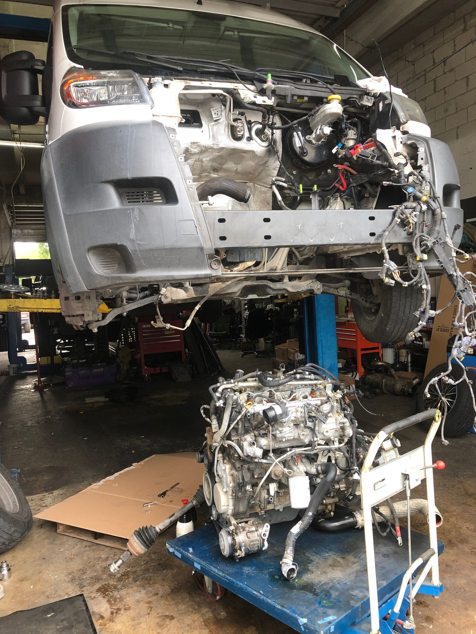 A van is being dismantled in a garage and the engine is sitting on a cart.