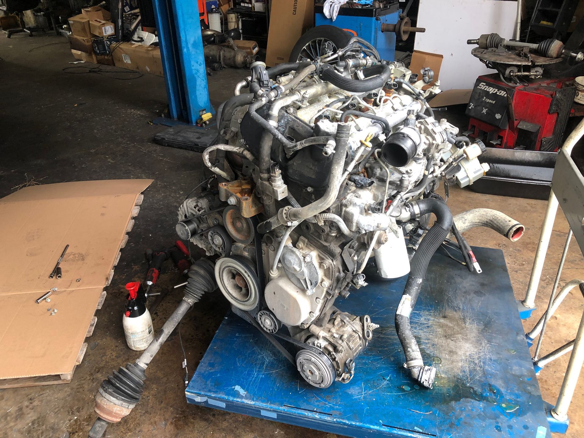 A car engine is sitting on top of a blue table in a garage.