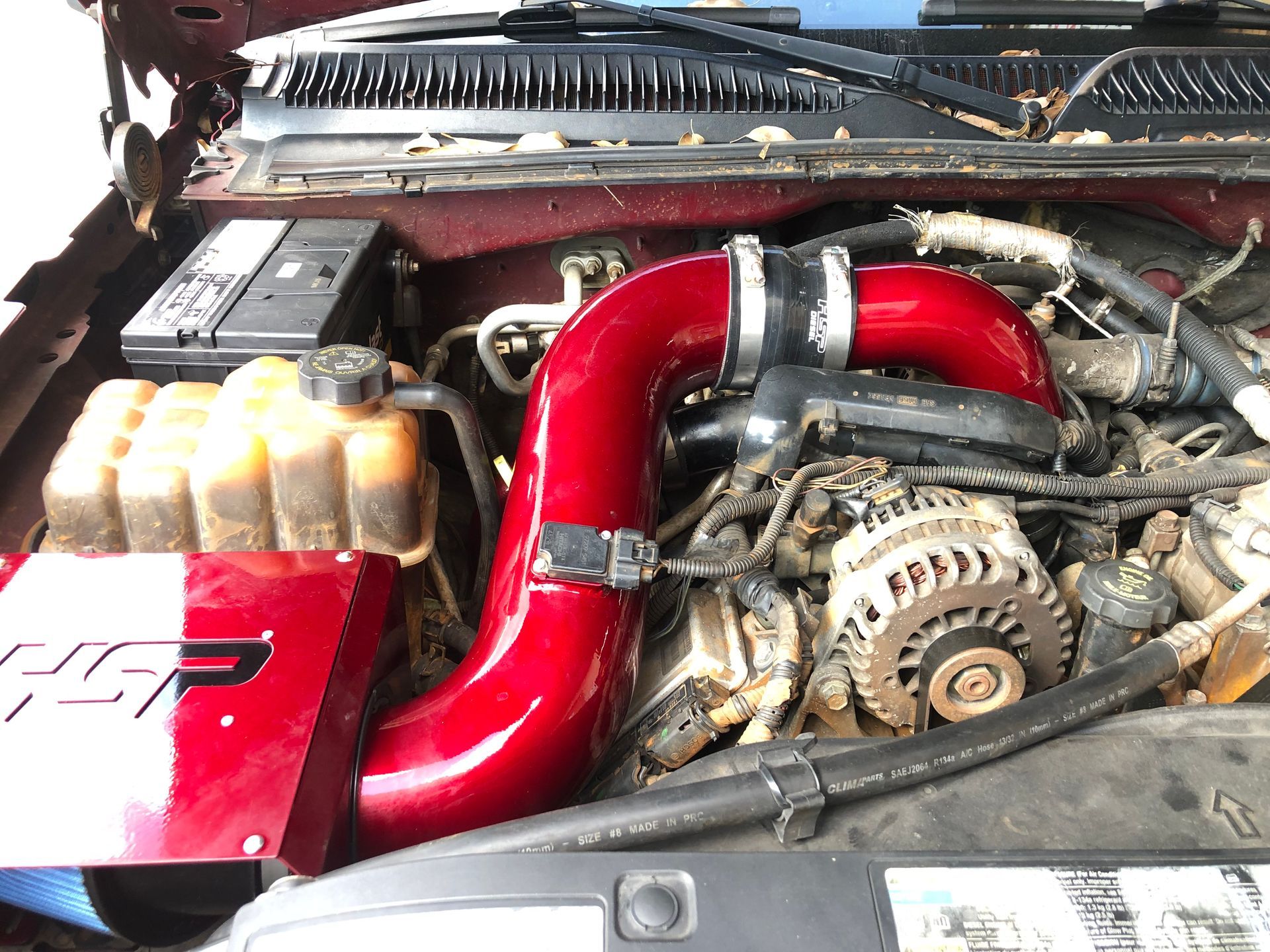 A close up of a car engine with a red pipe coming out of it.