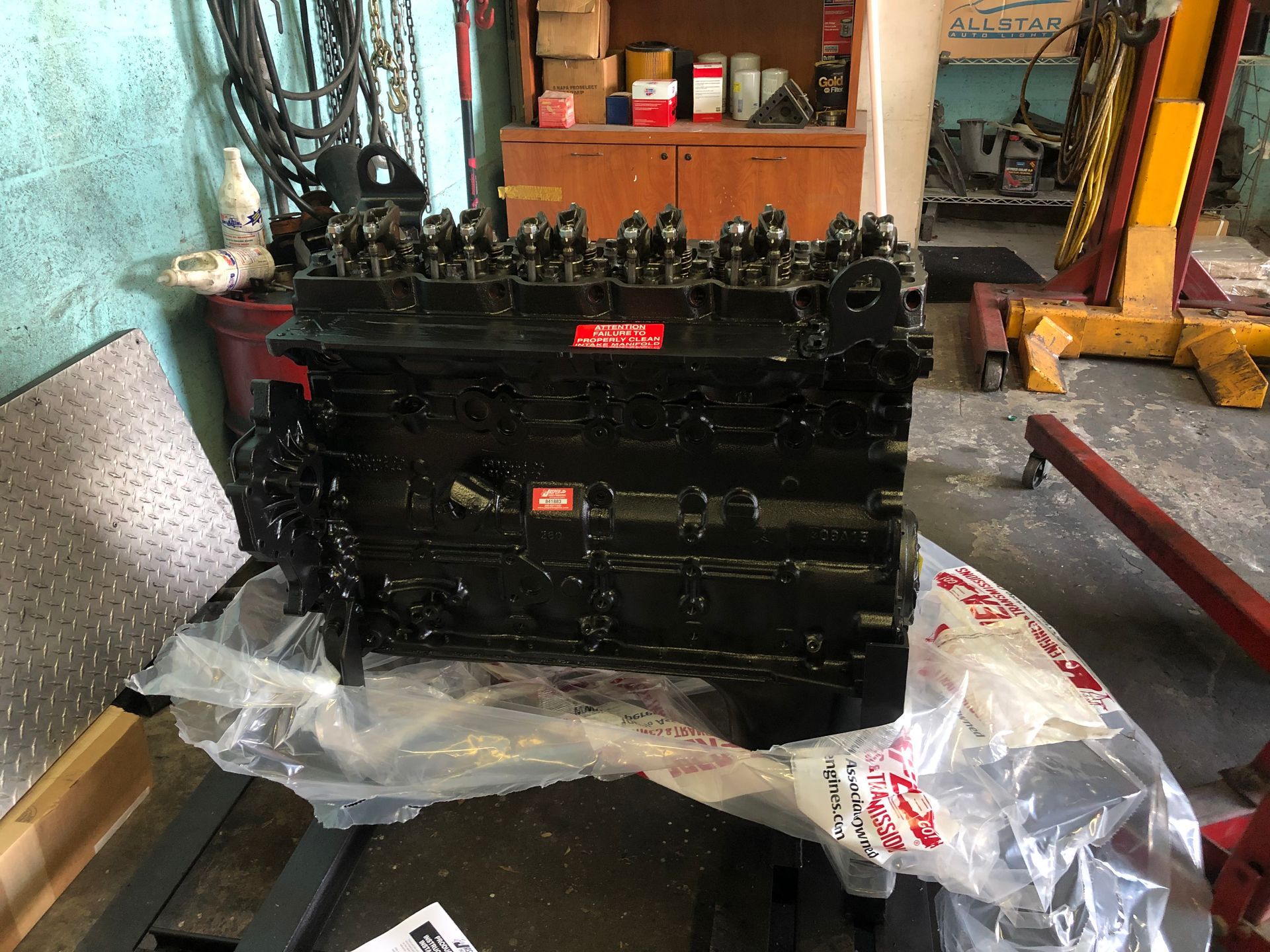 A black engine is wrapped in plastic and sitting on a table.