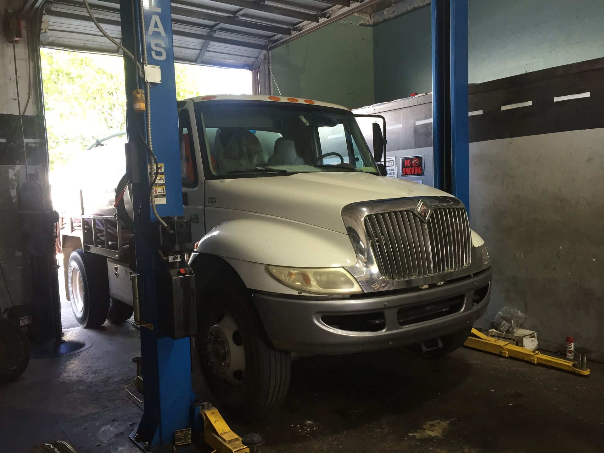 A white truck is sitting on a lift in a garage.