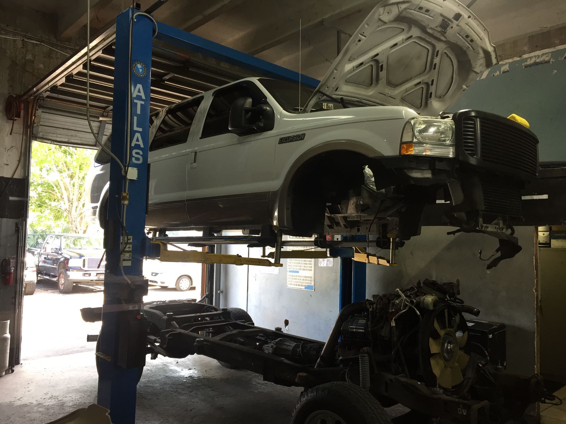 A white truck is sitting on a lift in a garage.