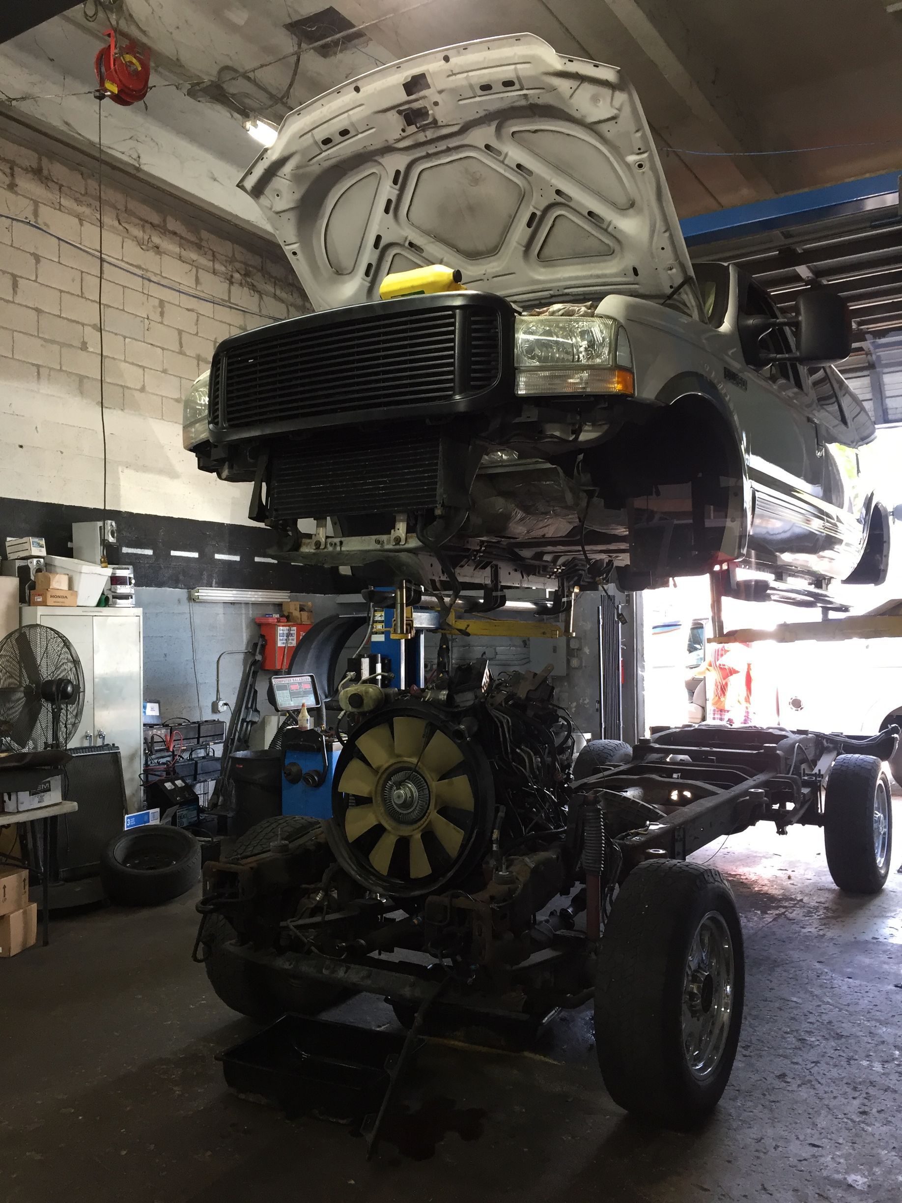 A truck is being worked on in a garage with the hood up.