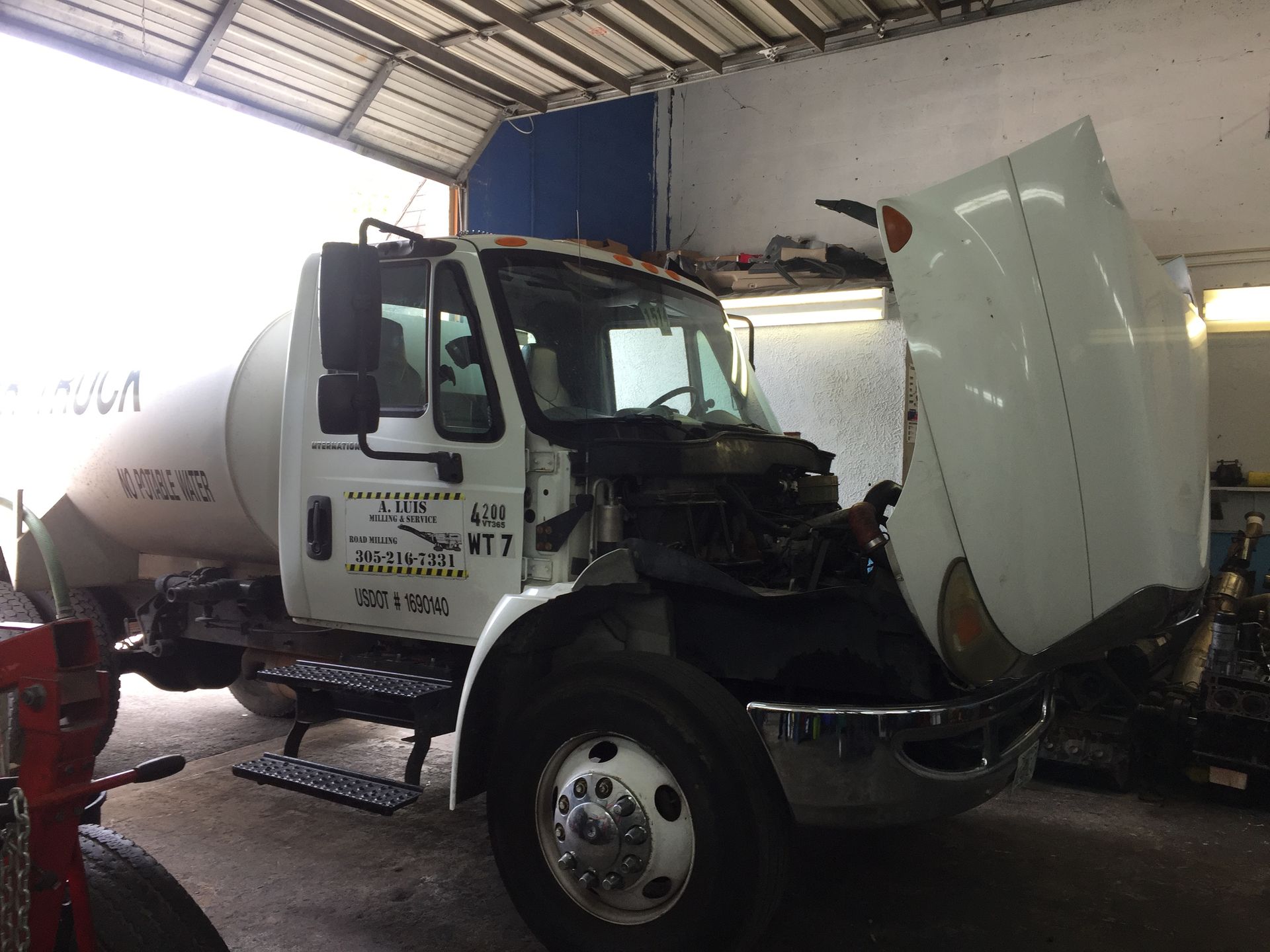 A white truck with the hood open in a garage