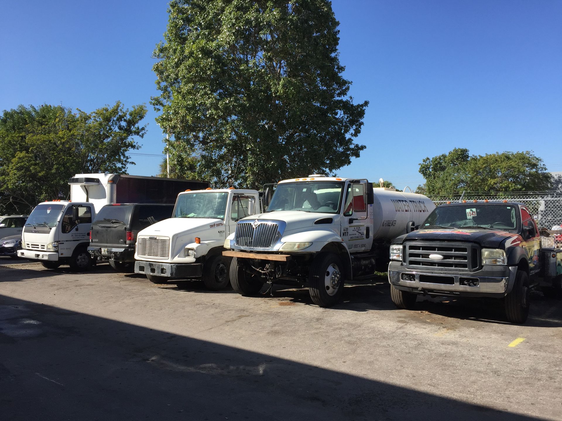 A row of trucks are parked in a parking lot.