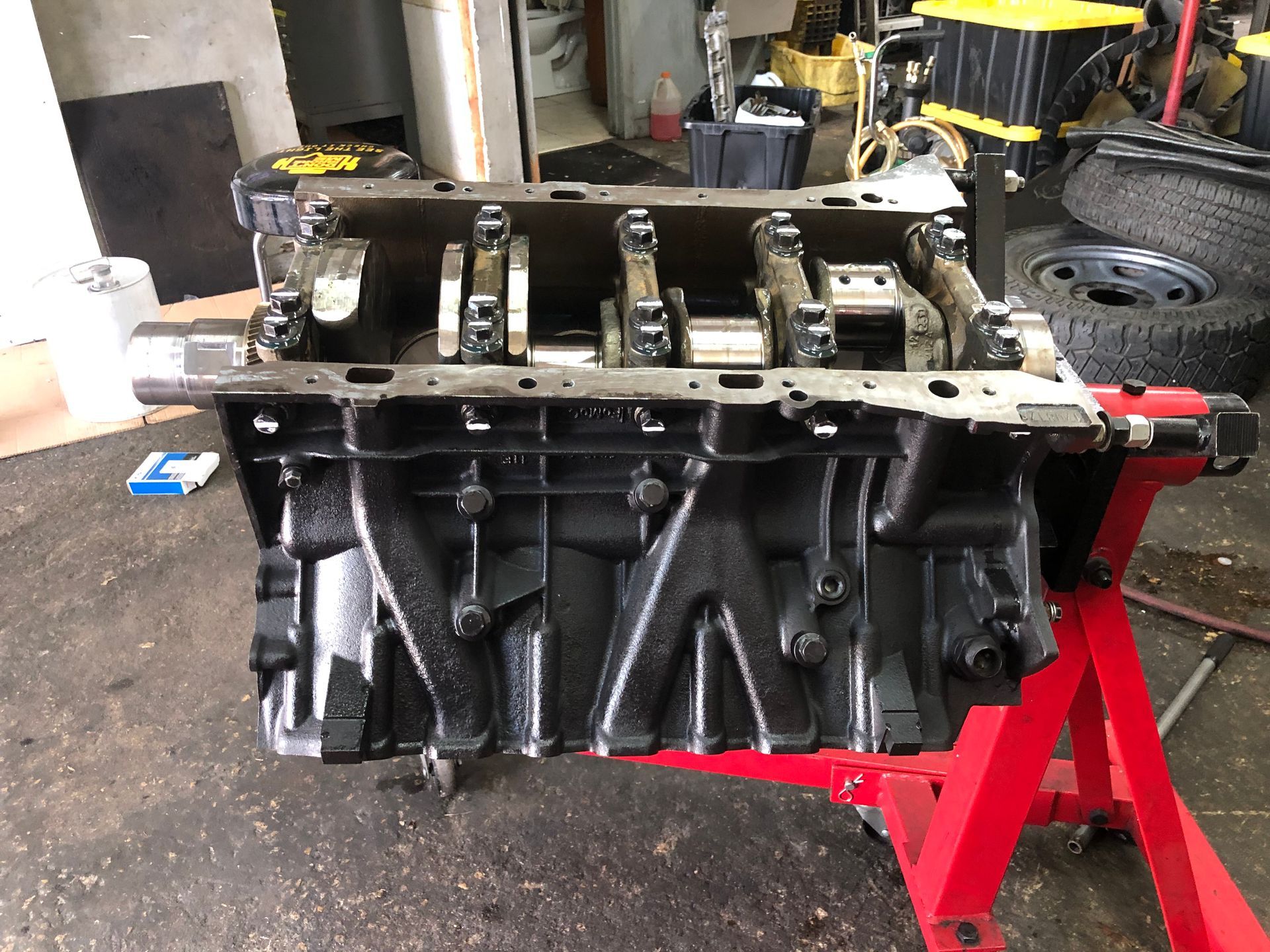 A black engine block is sitting on a red stand in a garage.