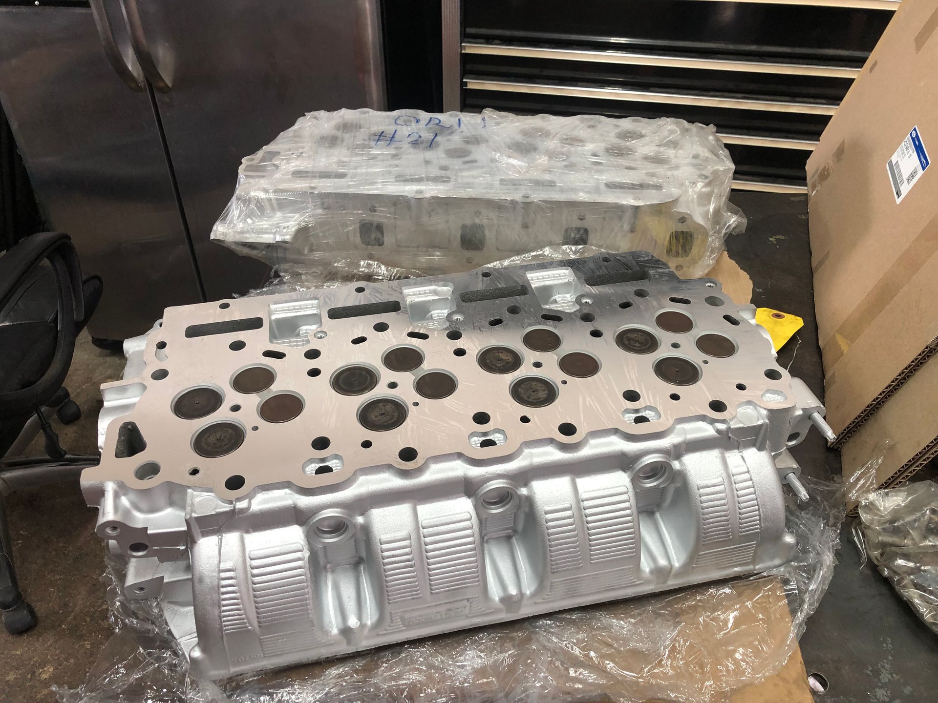 Two cylinder heads are stacked on top of each other on a table.