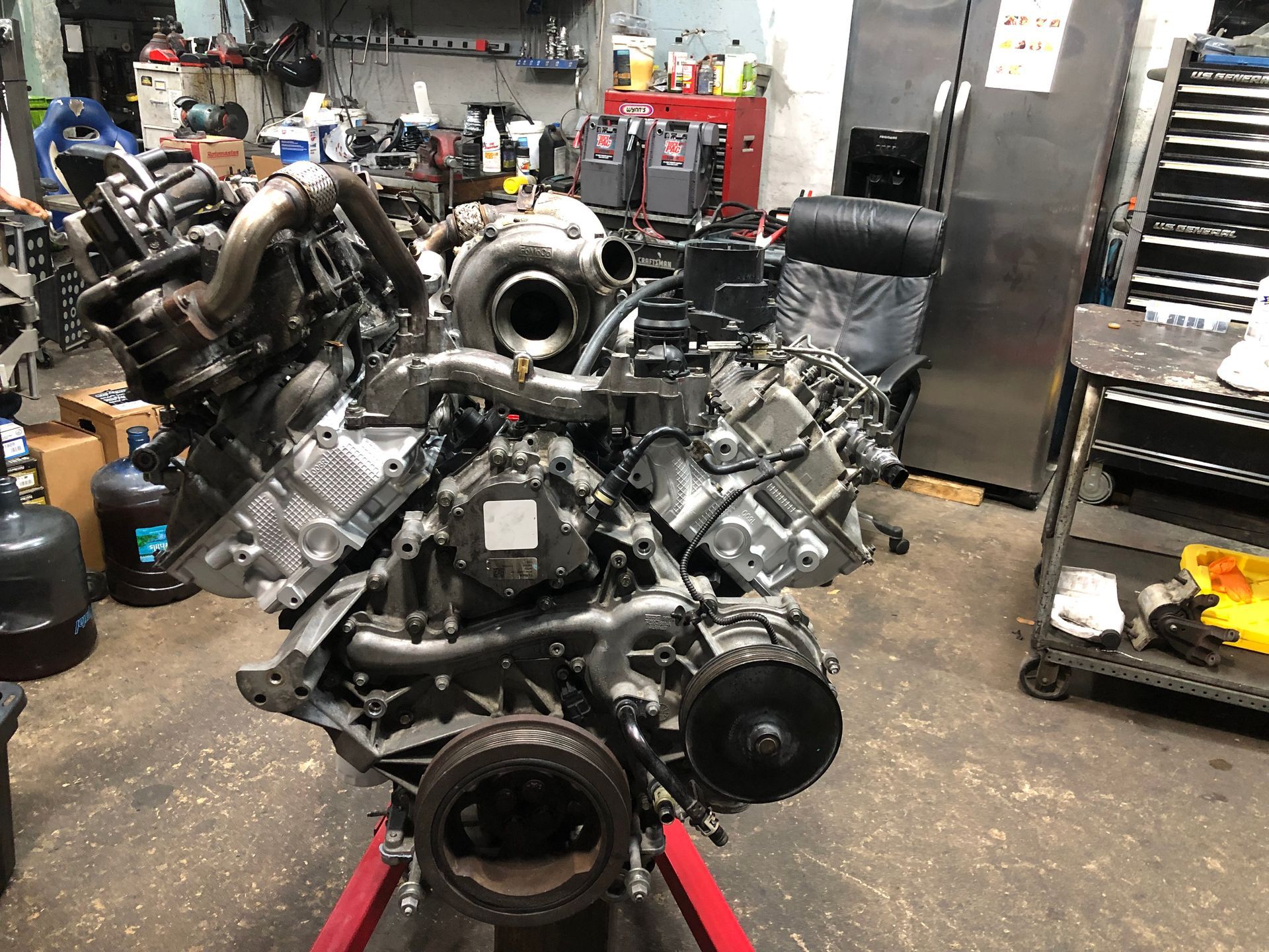 A large engine is sitting on a red stand in a garage.