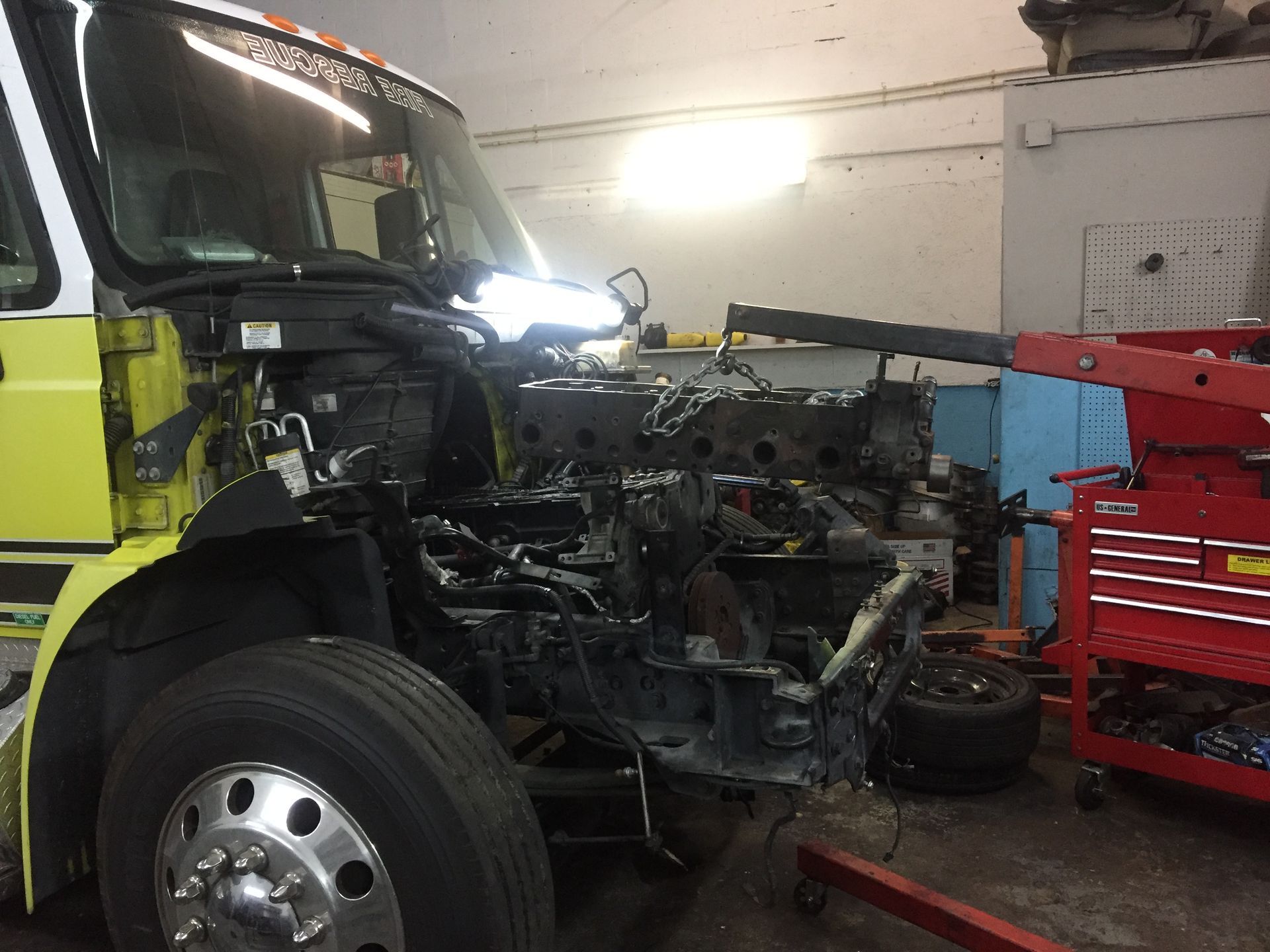 A yellow and white truck is being worked on in a garage.