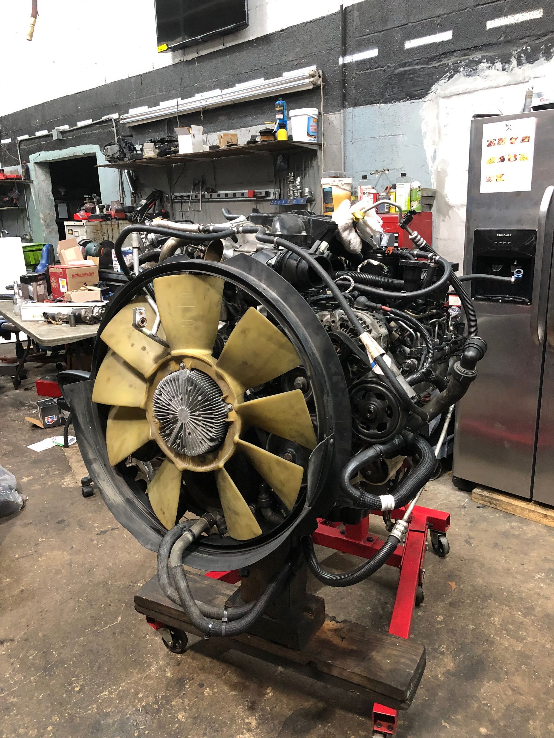 A large engine is sitting on a stand in a garage.