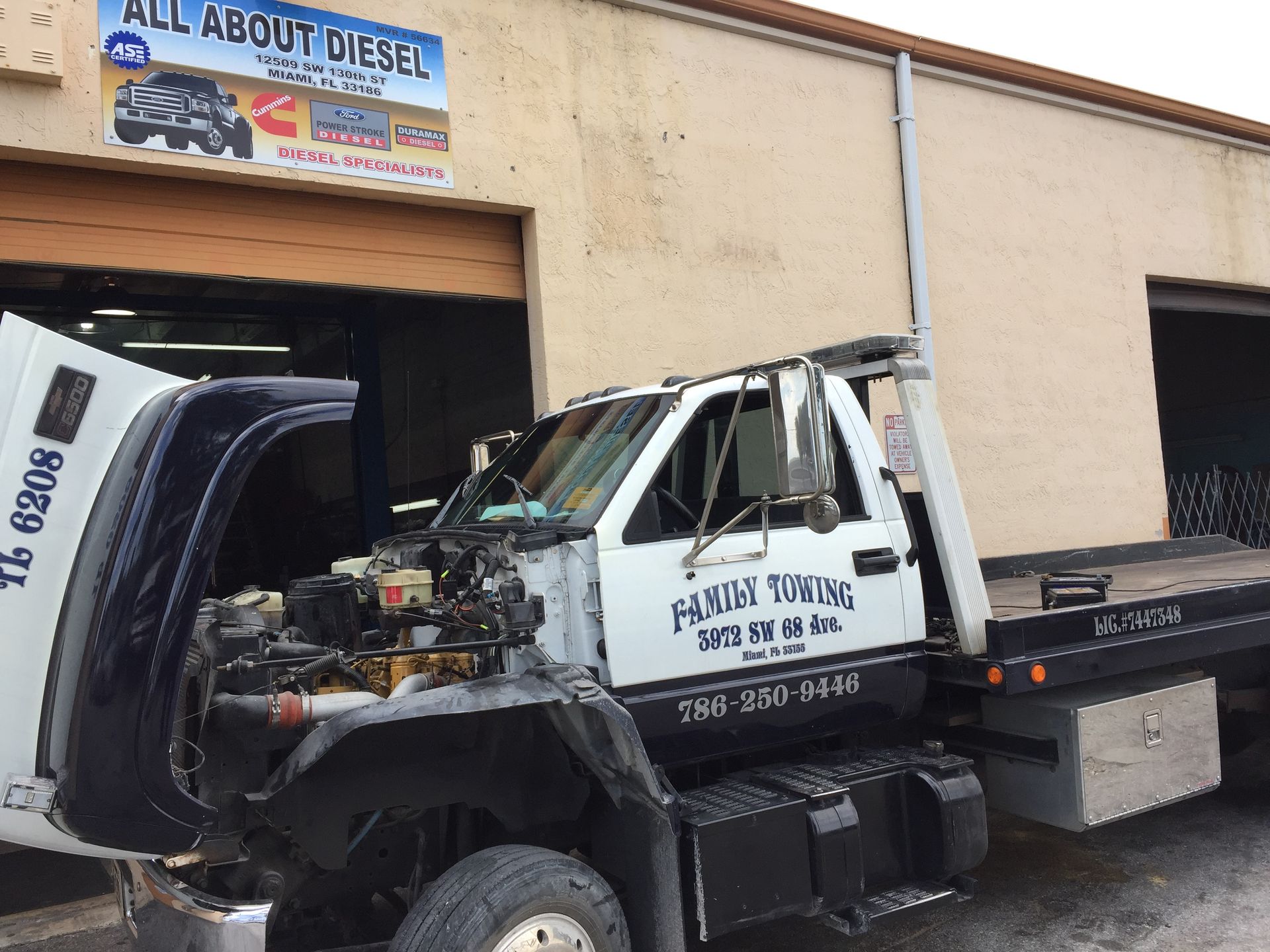 A tow truck is parked in front of a building that says all about diesel