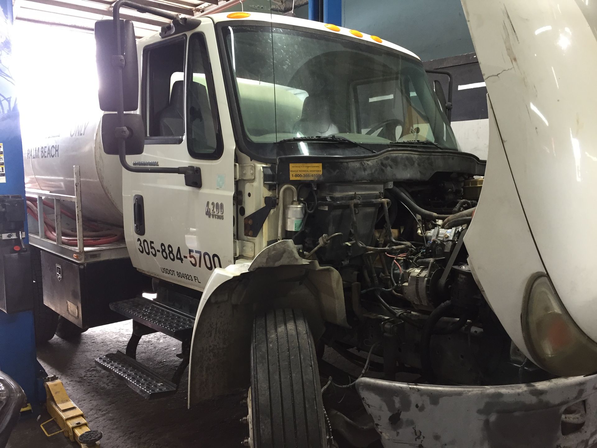 A white truck with the hood open is sitting in a garage.