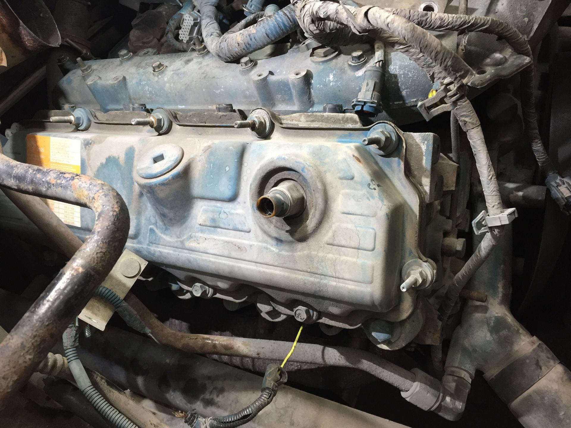 A close up of a dirty engine with a hose coming out of it.