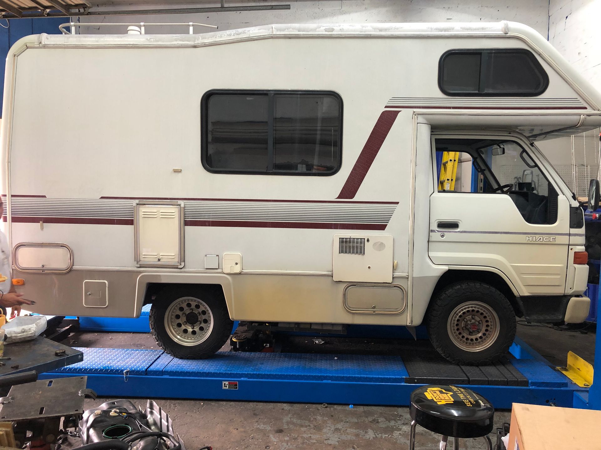 A white rv is parked on a lift in a garage.