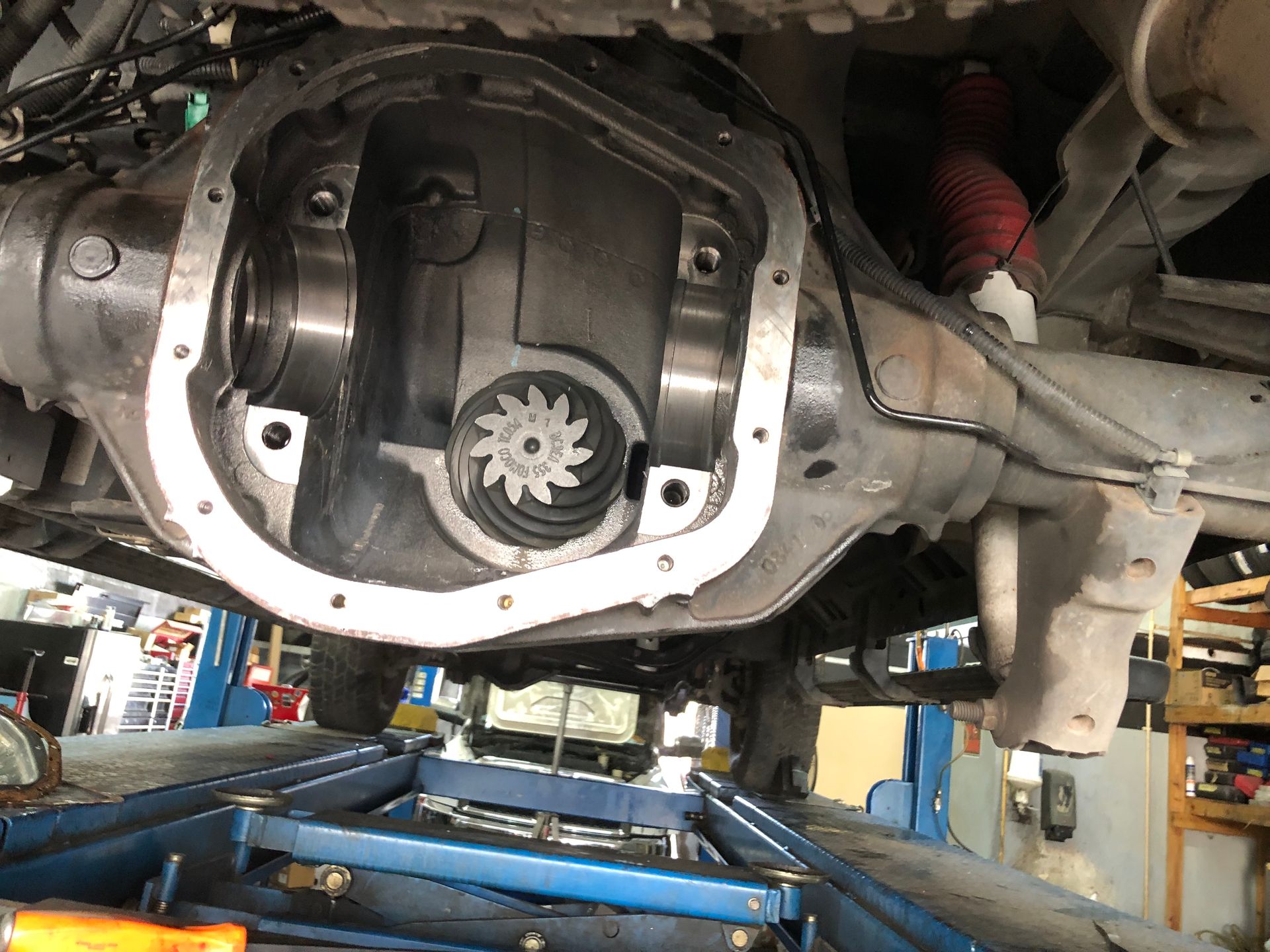 The rear differential of a car is being repaired in a garage.