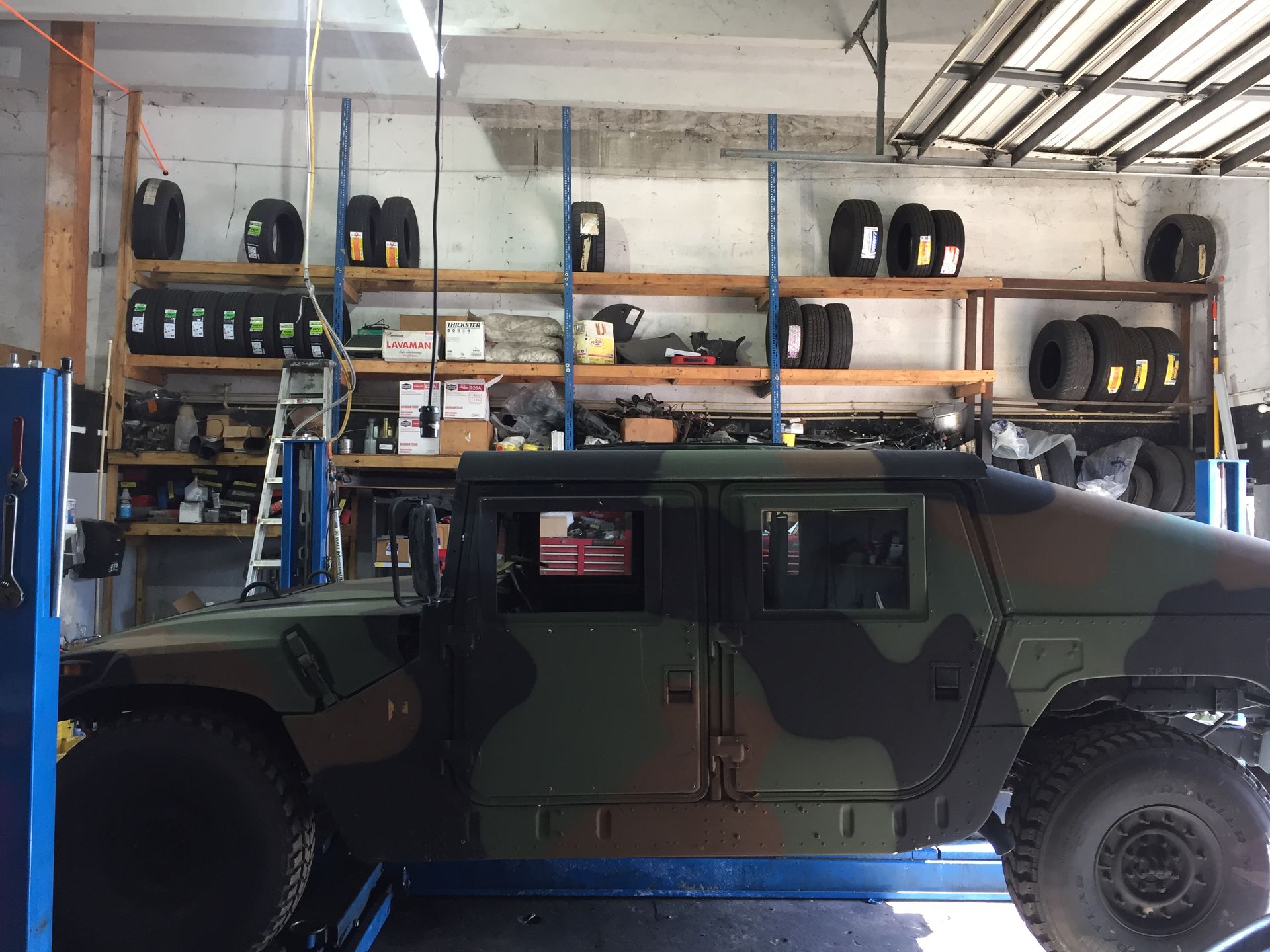 A military vehicle is parked on a lift in a garage.