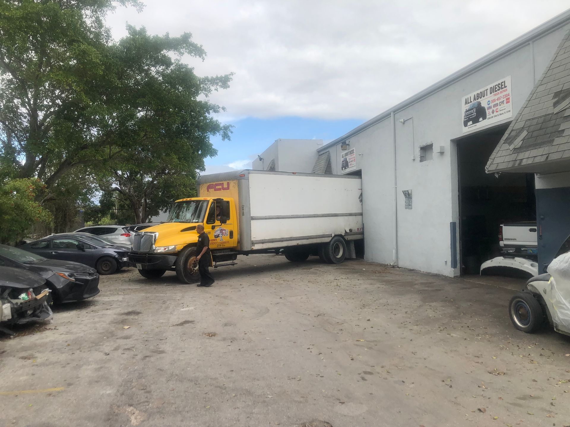 A yellow truck is parked in front of a white building.