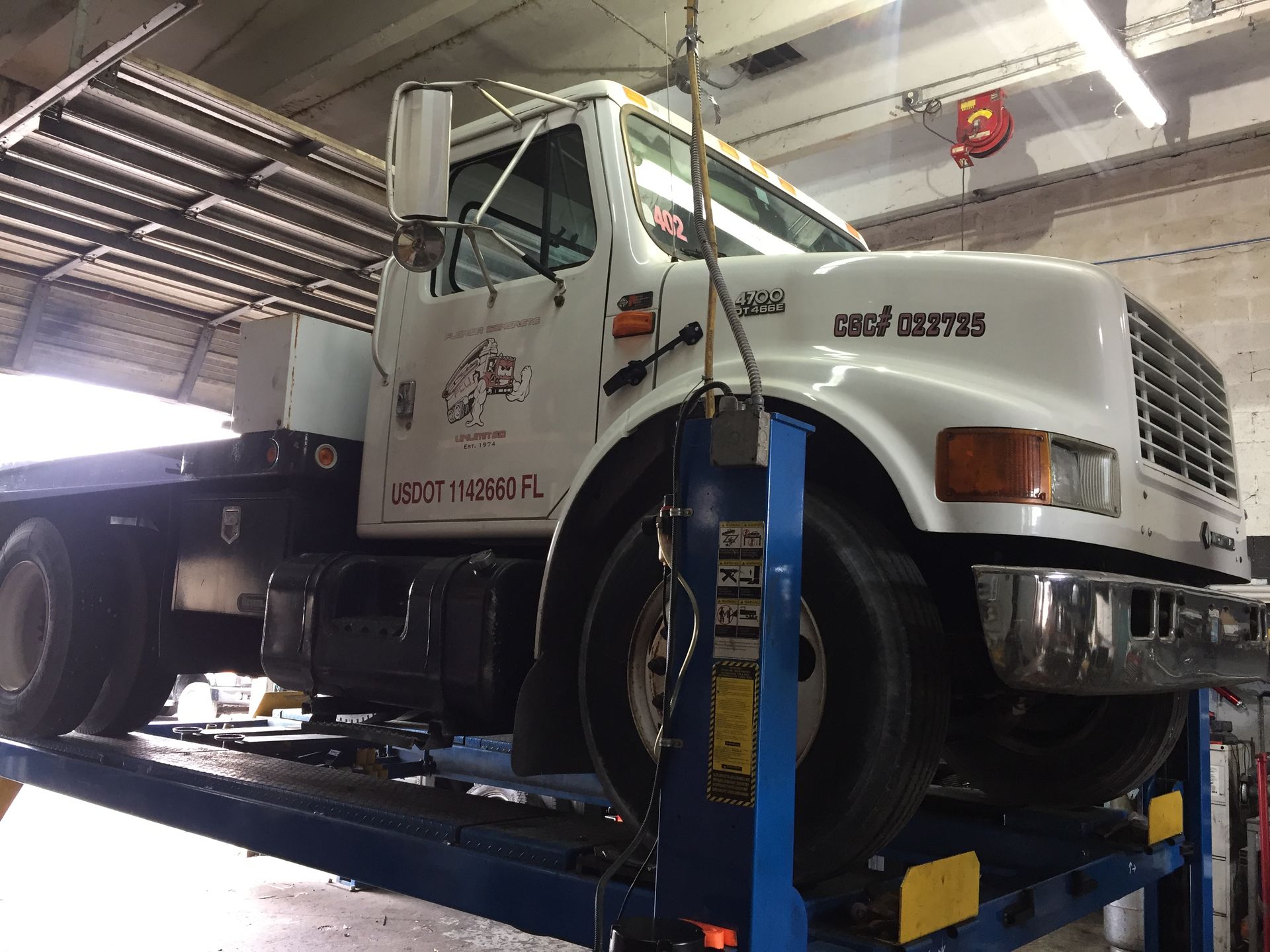 A white tow truck is on a lift in a garage