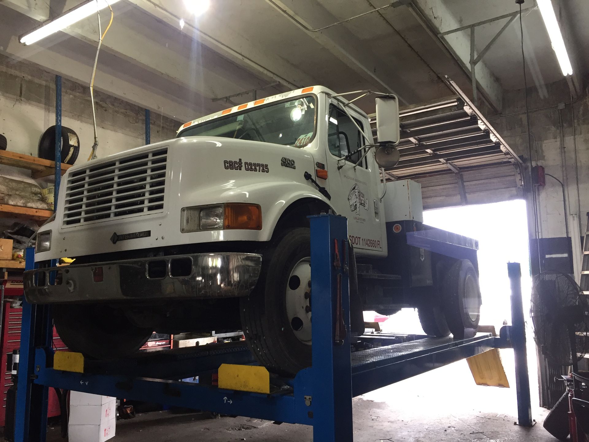 A white truck is sitting on a lift in a garage.