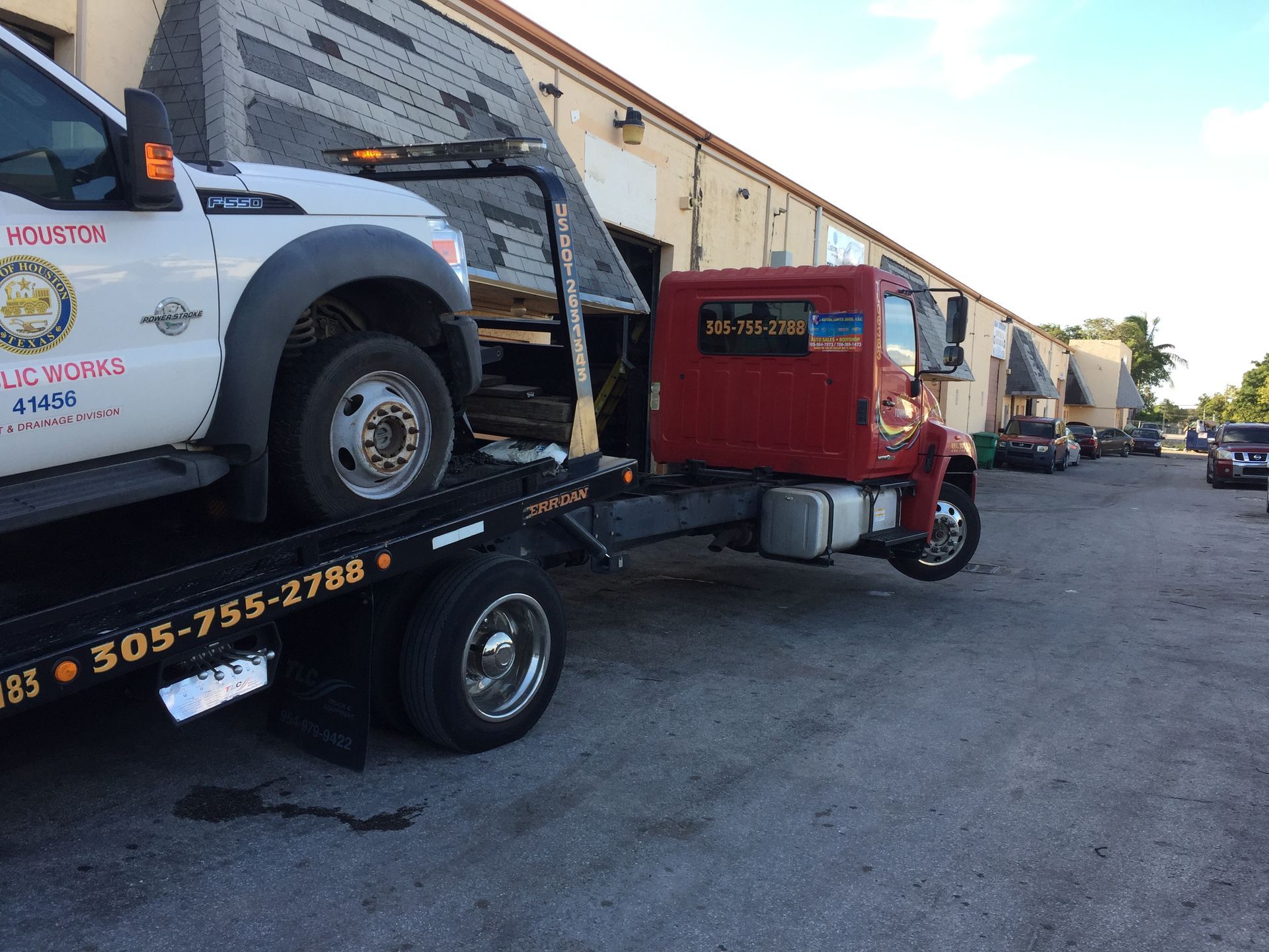 A white truck is being towed by a red tow truck