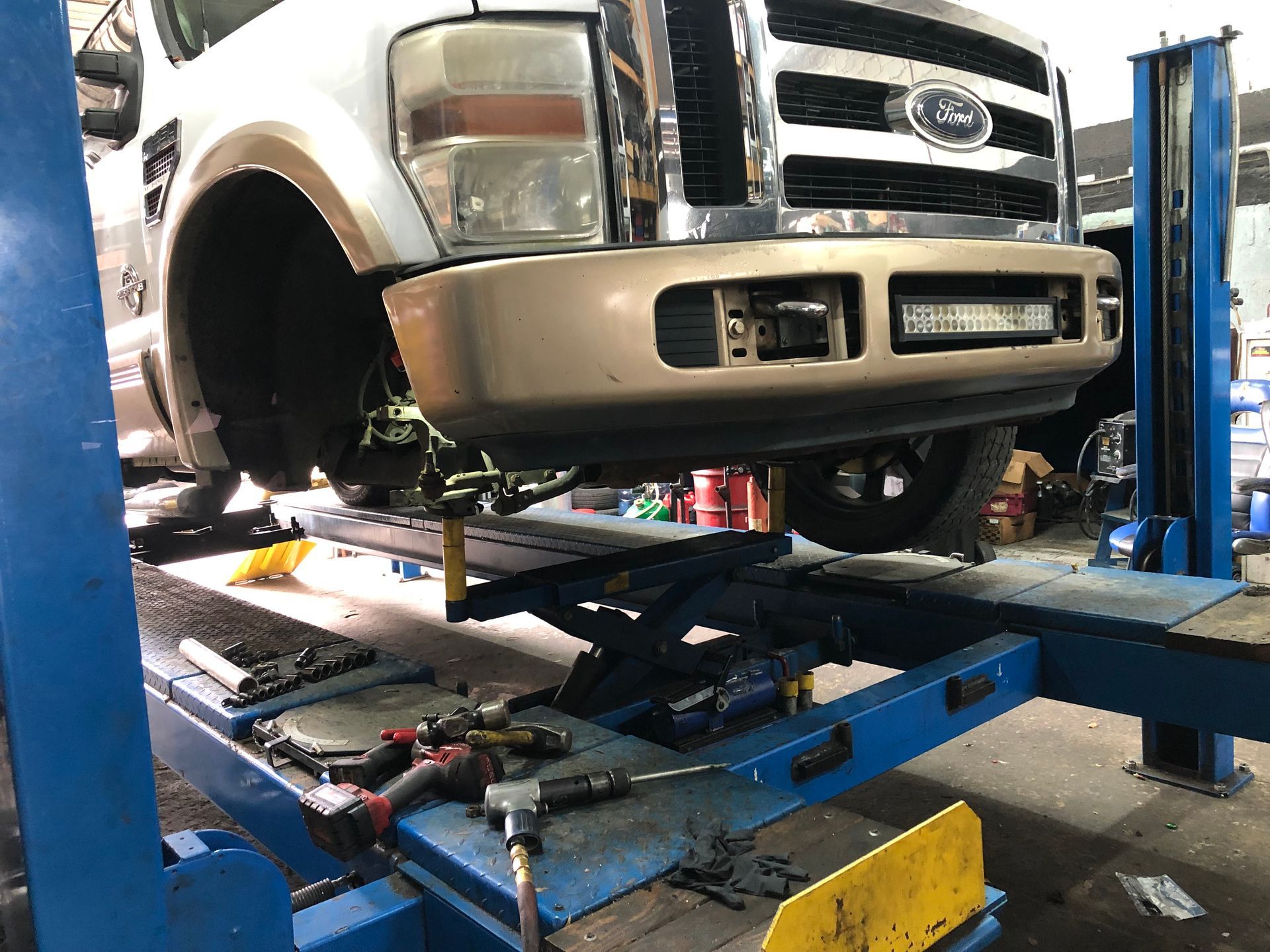 A ford truck is sitting on a lift in a garage.