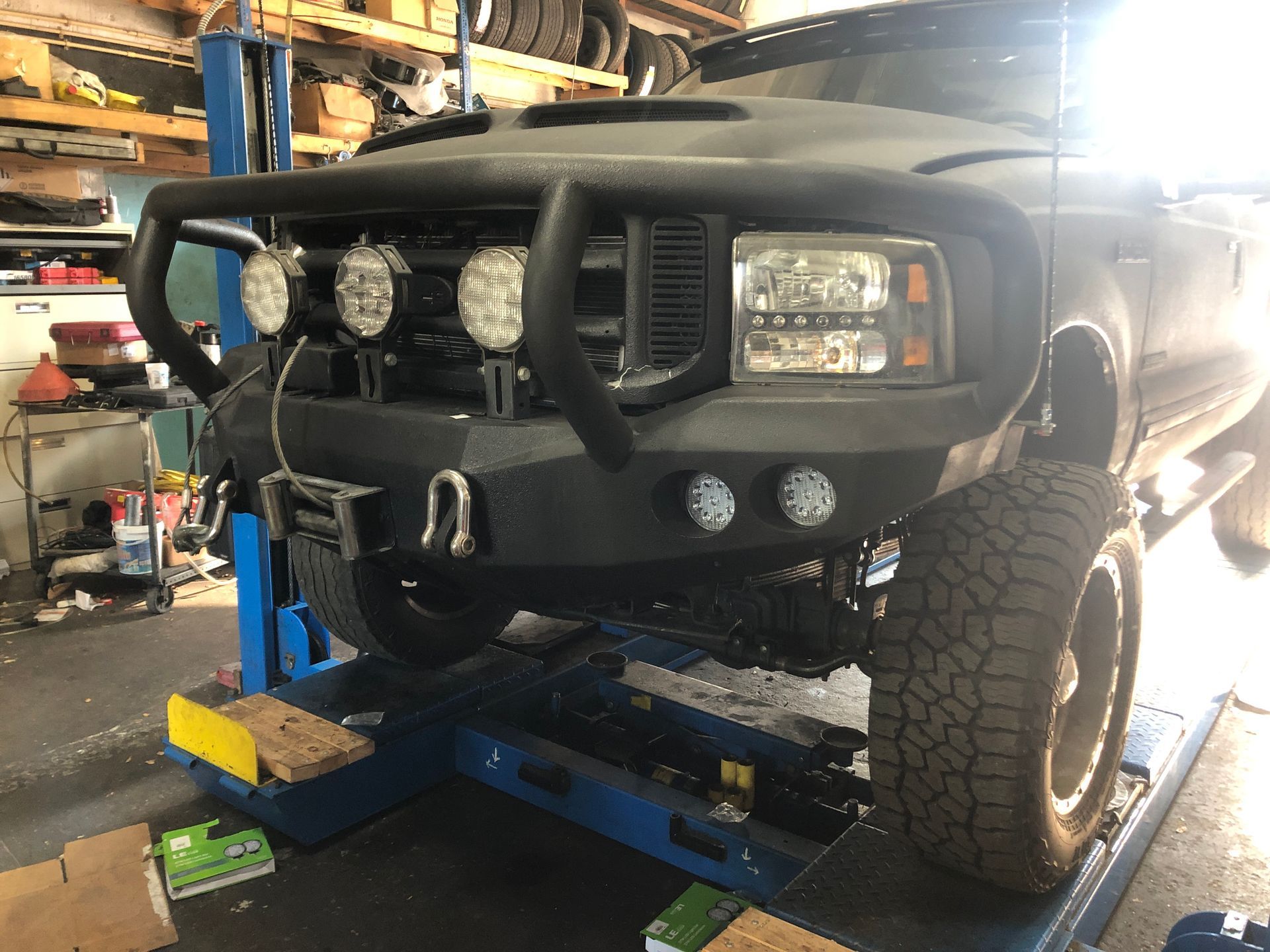 A black truck is sitting on a lift in a garage.