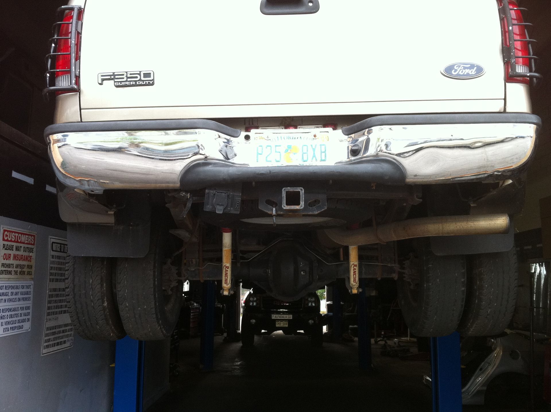 A white ford truck is on a lift in a garage