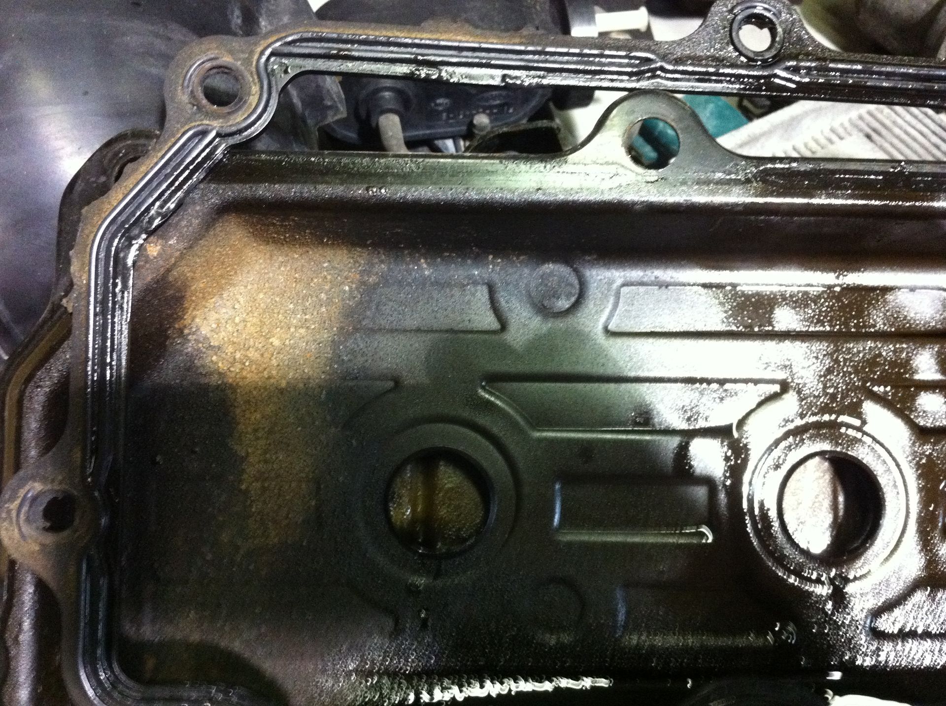 A close up of a dirty engine cover with a hole in it