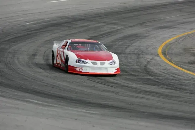 A red and white race car is driving on a track.