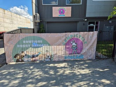 A Large Banner is Hanging on a Fence in Front of a Building — Signworld In Mitchell, ACT