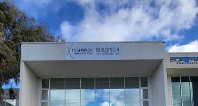A Green Aerial Lift is Parked in Front of a Large Building — Signworld In Mitchell, ACT