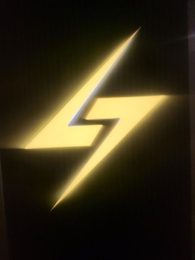 A Yellow Lightning Bolt is Glowing in the Dark on a Black Background — Signworld In Mitchell, ACT
