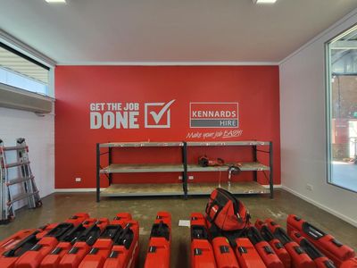A room with a red wall that says get the job done — Signworld In Mitchell, ACT