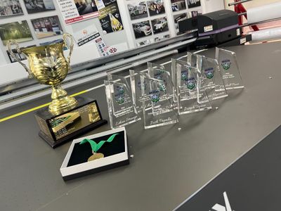 A Trophy is Sitting on Top of a Table Next to a Row of Trophies — Signworld In Mitchell, ACT