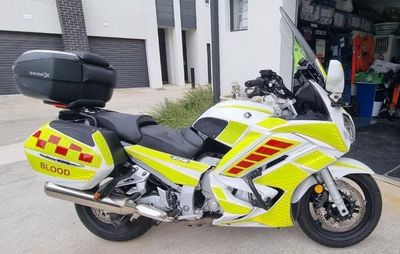 A Yellow and White Motorcycle is Parked in Front of a Garage — Signworld In Mitchell, ACT