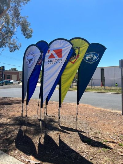 A Bunch of Flags Are Lined Up on the Side of the Road — Signworld In Mitchell, ACT