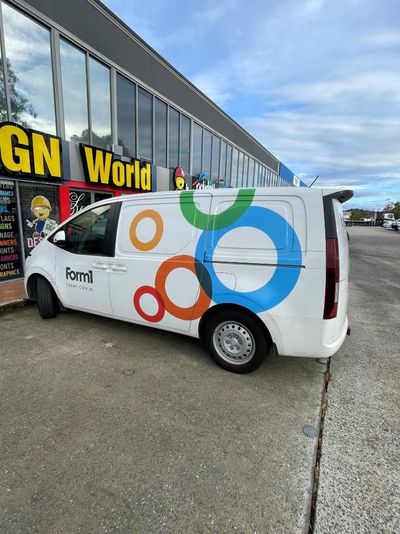 A White Van is Parked in Front of a Building That Says Gn World — Signworld In Mitchell, ACT