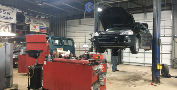 A car is sitting on a lift in a garage. | Keck's Repair Inc