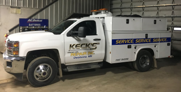 A white service truck is parked in a garage. | Keck's Repair Inc